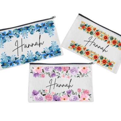 Three personalized pouches with A name written on them, adorned with different floral designs.