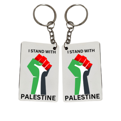 Two square keychains with a graphic of a raised fist in front of the Palestinian flag and text that reads ‘I STAND WITH PALESTINE.